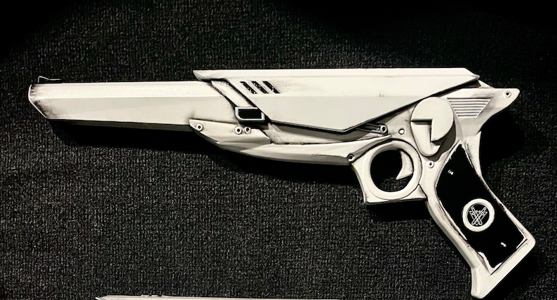 3D printed ray gun prop in white with black grips, shown from a side profile. Set against a black textured background to highlight the clean design. Perfect for MCR fans, collectors, and those seeking a unique ray gun replica.