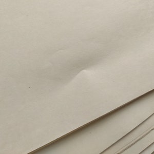 May include: A stack of off-white paper sheets. The top sheet has a slight crease in the center.