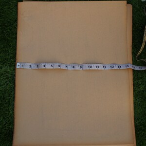 Op de afbeelding: Een stapel bruin papier met een meetlint eroverheen. Het lint meet 43 cm.