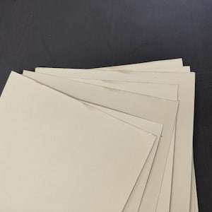 May include: A stack of off-white cardboard sheets, likely for crafting or scrapbooking.