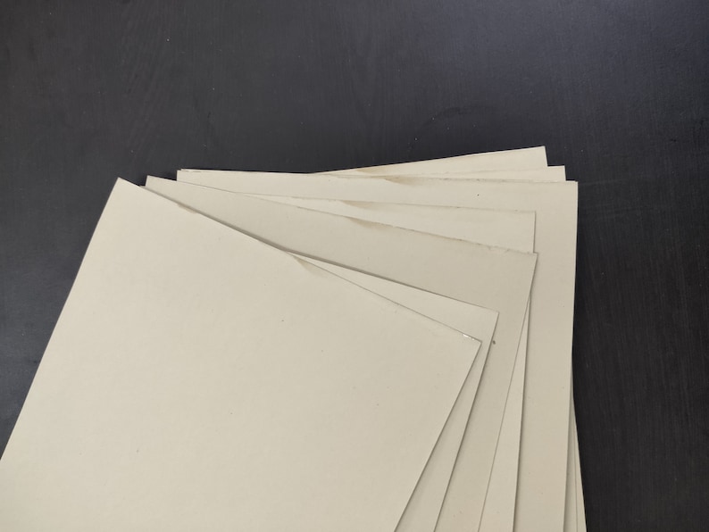 May include: A stack of off-white cardboard sheets, likely for crafting or scrapbooking.