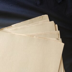 May include: A stack of off-white paper sheets with slightly uneven edges. The paper is folded in a fan shape, with the top sheet covering the others.