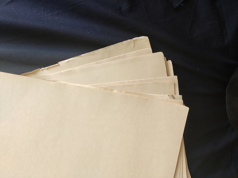 May include: A stack of off-white paper sheets with slightly uneven edges. The paper is folded in a fan shape, with the top sheet covering the others.