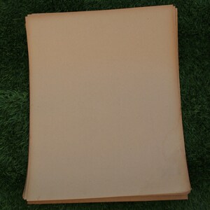 Op de afbeelding: Een stapel lichtbruine vellen papier met een licht ruwe textuur.