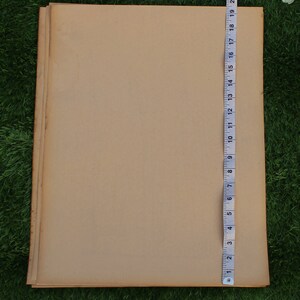 Op de afbeelding: Een stapel bruine papieren vellen met een meetlint langs de rechterrand. De tape meet tot 56 cm.