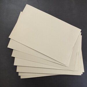 May include: A stack of eight beige cardboard sheets.