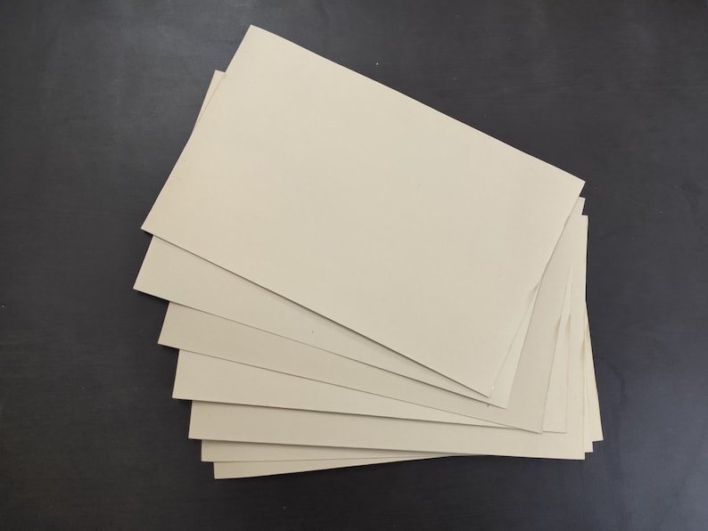 May include: A stack of eight beige cardboard sheets.