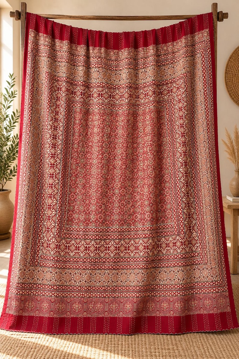 Puede incluir: Un tapiz rectangular de tela con una base de color rojo intenso y patrones geom&eacute;tricos y florales repetitivos en tonos crema y marr&oacute;n apagado. La tela presenta un dise&ntilde;o de bordes superpuestos con l&iacute;neas de costura verticales visibles.
