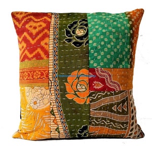 Puede incluir: Cojín cuadrado de patchwork con una variedad de patrones y colores de tela. El cojín presenta una mezcla de telas naranjas, rojas, verdes y amarillas, con diseños florales y geométricos. Las costuras blancas acentúan el patchwork.
