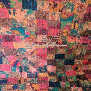 May include: A colourful patchwork quilt featuring a variety of fabrics in shades of pink, orange, green, and blue. The quilt is composed of stitched squares with floral and geometric designs. The visible stitching adds texture to the handmade textile.
