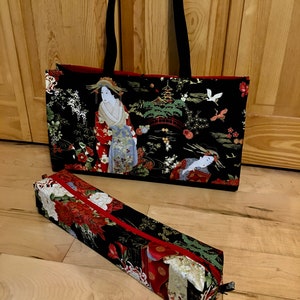 May include: Black tote bag and pencil case featuring a Japanese geisha design. The tote bag has black handles and a red interior. The pencil case has a red zipper. Both items display a colorful print with geishas, flowers, and pagodas.