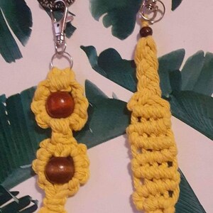 May include: Two yellow macrame keychains with wooden beads. One keychain has a tassel and the other has a beaded design.