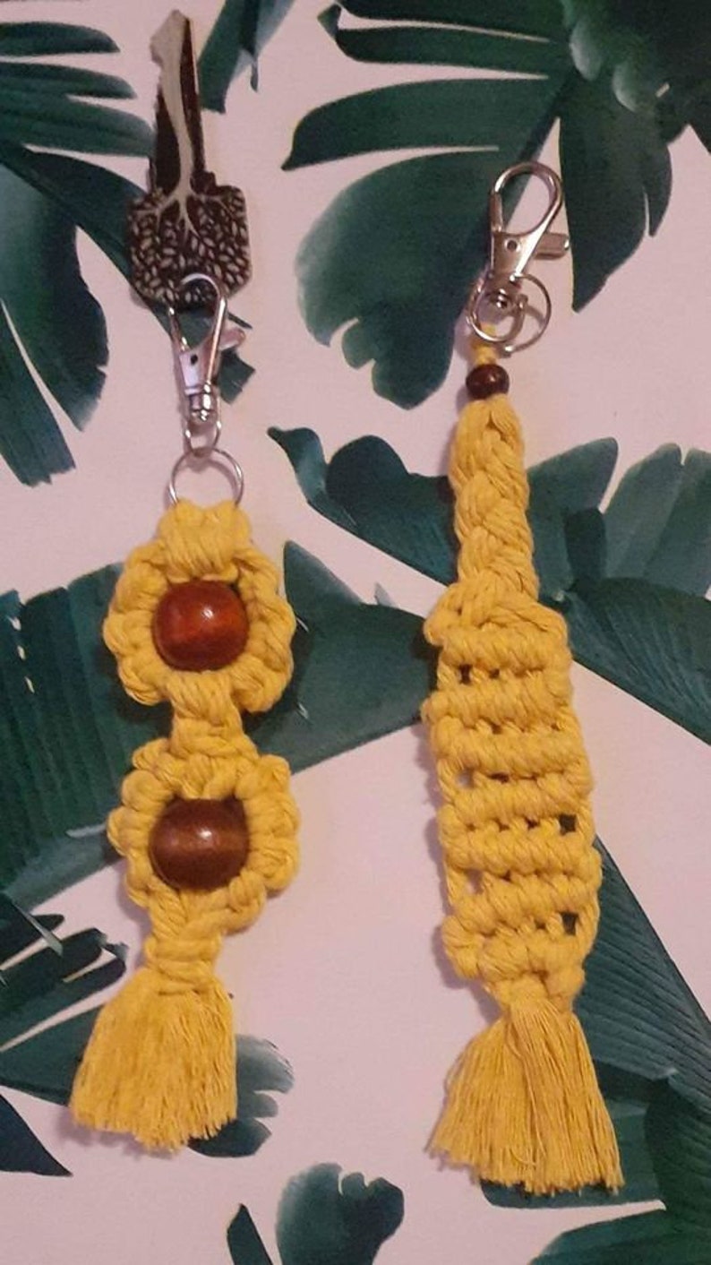 May include: Two yellow macrame keychains with wooden beads. One keychain has a tassel and the other has a beaded design.