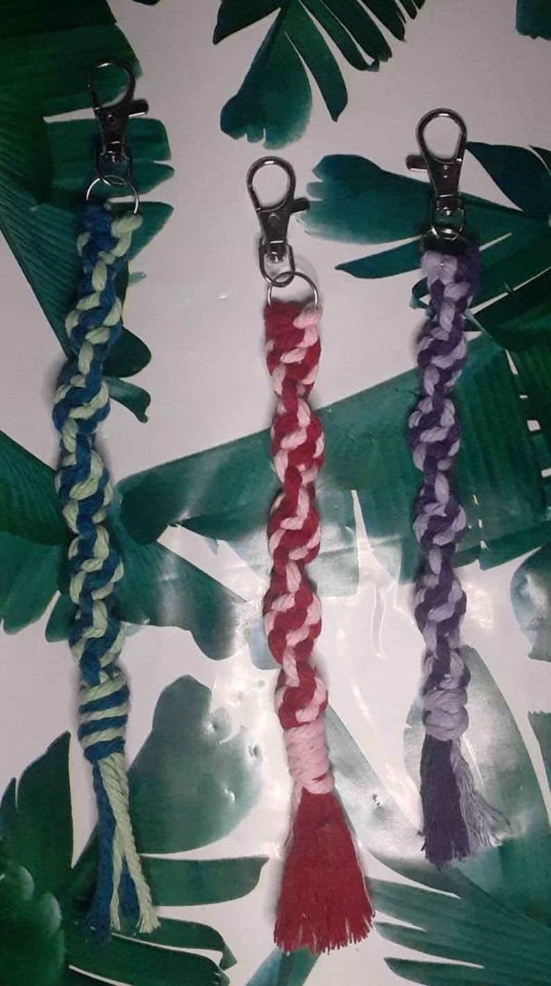 May include: Three colorful braided keychains with silver key rings. The keychains are made of a thick, twisted cord. The colors are blue and green, pink and red, and purple and white.