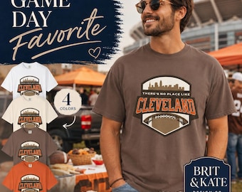 May include: A brown t-shirt with a Cleveland design, featuring a skyline and football field graphic. The image shows four different shirt colours: white, beige, brown, and orange. The text reads "Game Day Favourite."