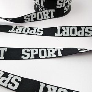 May include: Black elastic ribbon with the word "SPORT" printed in white letters.