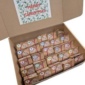 May include: A festive advent calendar in a cardboard box, containing 24 numbered parcels. Each parcel is wrapped in brown paper and tied with a red ribbon. A card with "MERRY CHRISTMAS" is displayed.