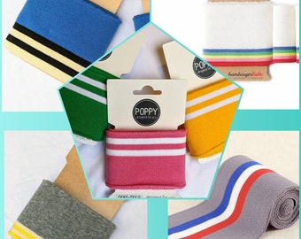 May include: Assortment of colourful knit fabric cuff bracelets with white stripes. The cuffs are packaged on cards with the brand name "POPPY" and the text "designed for you".