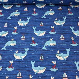 May include: Blue fabric with a repeating pattern of whales, seagulls, anchors, and sailboats. The whales are light blue with white bellies and are swimming in a wavy blue sea. The seagulls are white with black eyes and are perched on anchors. The anchors are red with white ropes. The sailboats are red and white.