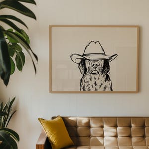 Puede incluir: Una ilustraci&oacute;n en blanco y negro de un perro con un sombrero de vaquero. El perro est&aacute; mirando directamente al espectador. La ilustraci&oacute;n est&aacute; enmarcada y colgada en una pared de una sala de estar.