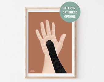 May include: A framed art print featuring a hand and a black cat paw touching. The background is a solid terracotta color. The text "Different Cat Breed Options" is in a green circle in the upper right corner. The artist's name is in the lower left corner.