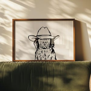Puede incluir: Un dibujo en blanco y negro de un perro con un sombrero de vaquero. El perro est&aacute; mirando directamente al espectador. La imagen est&aacute; enmarcada en un marco de madera marr&oacute;n.