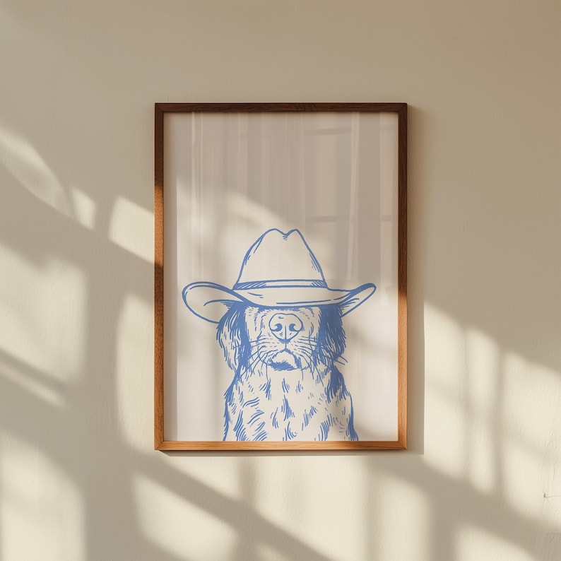 May include: A framed print featuring a blue line drawing of a dog wearing a cowboy hat. The artwork is set against a neutral background, framed in a wooden frame. The dog's face is detailed with visible fur and facial features.