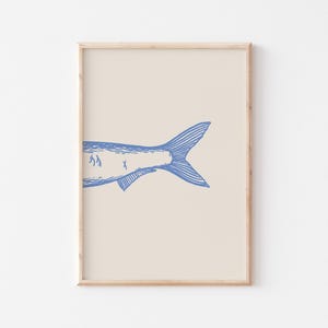May include: A framed print of a blue line drawing of a fish tail on a cream background.