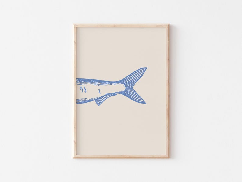 May include: A framed print of a blue line drawing of a fish tail on a cream background.