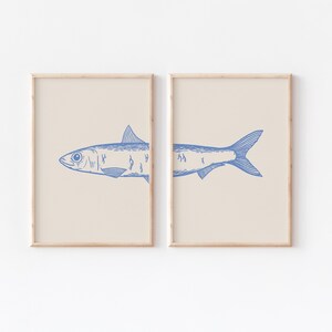 May include: Two framed prints of a blue line drawing of a fish on a beige background. The fish is split between the two frames.