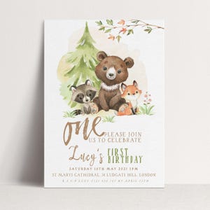 May include: A white invitation card featuring watercolor illustrations of a raccoon, bear, and fox. The card reads "One" and "Lucy's First Birthday" with event details. The design includes a green tree and floral accents.