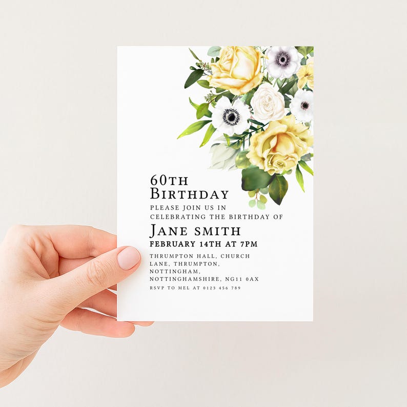 A hand holding a white invitation card with a floral design and text inviting guests to a birthday celebration.