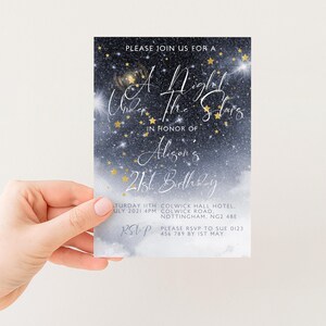 a hand holding a birthday invitation card with a starry night sky background.