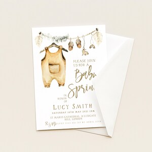 May include: Baby shower invitation featuring a watercolor illustration of a baby outfit hanging on a clothesline with small shoes, a rabbit, and a rainbow. The invitation includes the text "Please join us for a Baby Sprin" and event details.