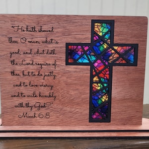 May include: Wooden cross with a stained glass design in rainbow colors. The cross is on a stand and has a quote from Micah 6:8 engraved on the wood: "He hath shewed thee, O man, what is good, and what doth the Lord require of thee, but to do justly, and to love mercy, and to walk humbly with thy God?" Micah 6:8