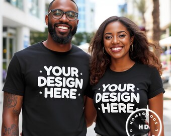 Könnte beinhalten: Zwei Personen tragen schwarze T-Shirts mit dem weißen Text "YOUR DESIGN HERE". Die Shirts sind kurzärmlig. Das Bild wurde im Freien mit unscharfem Hintergrund aufgenommen.