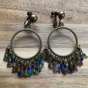 Dangling bronze hoop clip on earrings with rainbow beaded fringe