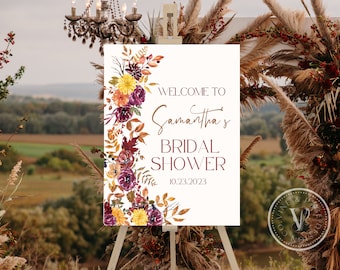 May include: A white sign with a floral wreath border in shades of red, orange, and yellow. The sign reads "Welcome to Samantha's Bridal Shower 10.23.2023".