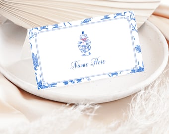 May include: Blue and white floral place card with a blue and white porcelain vase with a red ribbon. The text "Name Here" is printed on the card.