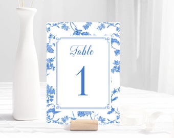 May include: Blue and white table number card with a floral pattern and the text "Table 1" in a black frame.