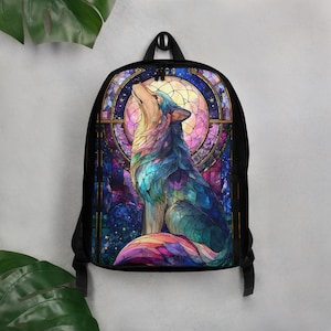 May include: A black backpack featuring a vibrant, multi-colored graphic of a wolf howling at a circular moon. The design mimics a stained glass window with intricate patterns in shades of blue, purple, pink, and gold, set against a dark frame.