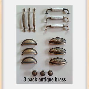May include: An assortment of antique brass cabinet hardware, including handles, pulls, and knobs. The image showcases different designs, such as bar pulls, cup pulls, and knobs, all in a warm, aged brass finish. The text "3 pack antique brass" is visible.
