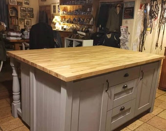 May include: A large kitchen island with a light wood countertop and a gray painted base. The base features drawers and cabinet doors with black hardware. The island has a classic design and is set on a tiled floor.