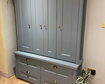 May include: A large, gray-blue wooden cabinet with four doors and four drawers. The cabinet has brass-colored hardware and a rectangular shape. The text "THIS IS OUR HAPPY PLACE" is visible on top of the cabinet.