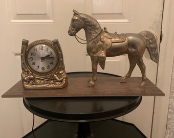 Miniature table clock to please rodeo lover or ranch person watchface. featuring a charm of a horse within a spur on a silver e.g.o
