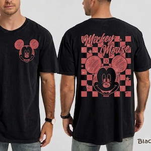 May include: Black t-shirt featuring a red Mickey Mouse graphic on the front and back. The back design includes a checkered pattern and the words "Mickey Mouse". The shirt has a vintage, distressed look.