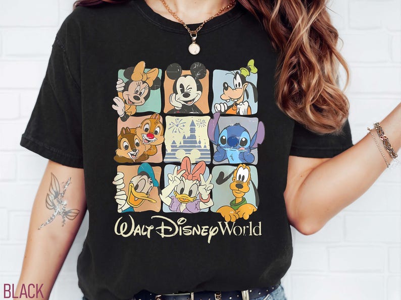 Op de afbeelding: Zwart T-shirt met een kleurrijk raster van Disney-personages, waaronder Mickey Mouse, Minnie Mouse, Goofy en Stitch. De tekst "Walt Disney World" staat eronder in een sierlijk lettertype.