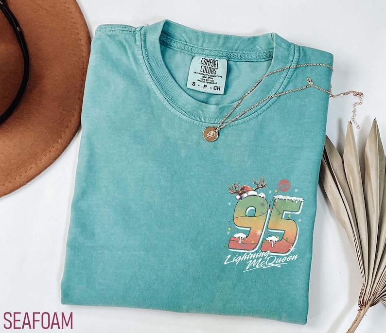 Puede incluir: Camiseta verde agua con un gr&aacute;fico navide&ntilde;o del n&uacute;mero 95 con un reno y el texto "Lightning McQueen".