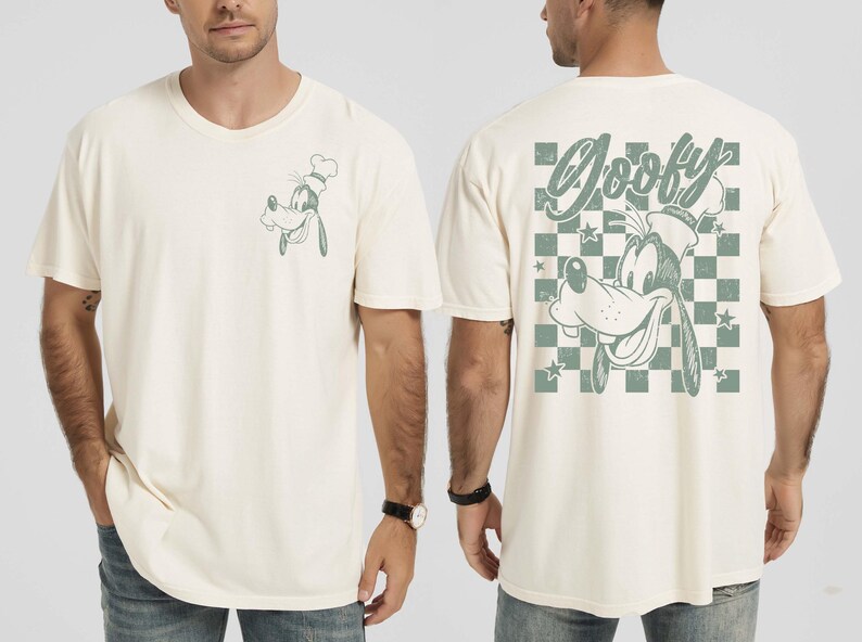 May include: Cream-colored t-shirt featuring a cartoon image of Goofy wearing a chef's hat. The front has a small image of Goofy, while the back displays a larger design with the word "Goofy" and a checkered pattern. The design is in a muted green.