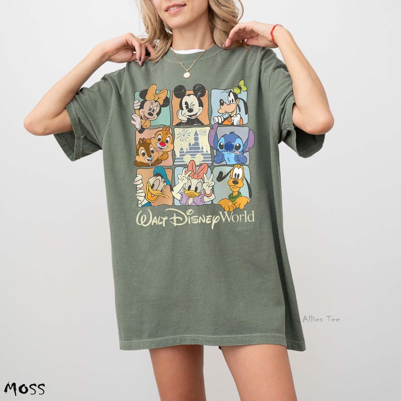 Op de afbeelding: Mosgroen T-shirt met een rasterontwerp met verschillende Disney-personages zoals Mickey Mouse en Donald Duck. De woorden "Walt Disney World" staan eronder. Het shirt heeft korte mouwen en een losse pasvorm.